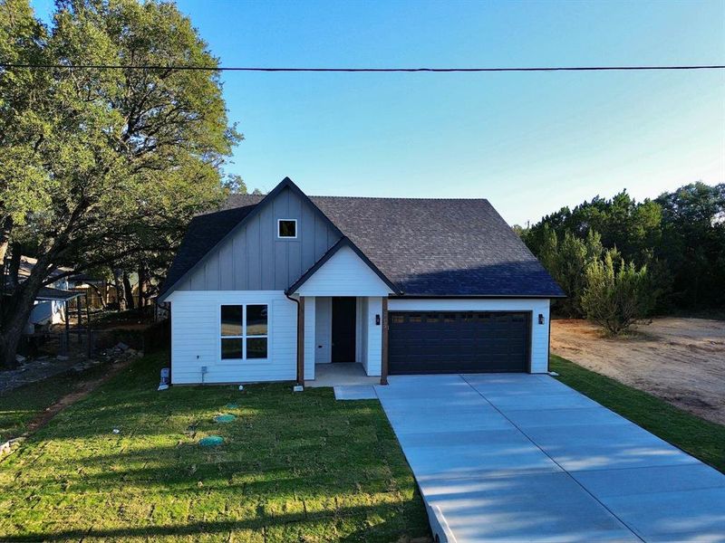 Modern inspired farmhouse with a garage and a front lawn