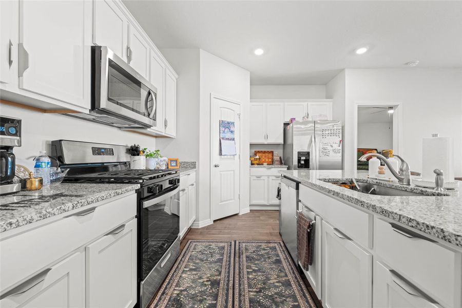 A well-appointed kitchen showcases white cabinetry, granite countertops, and modern stainless steel appliances.