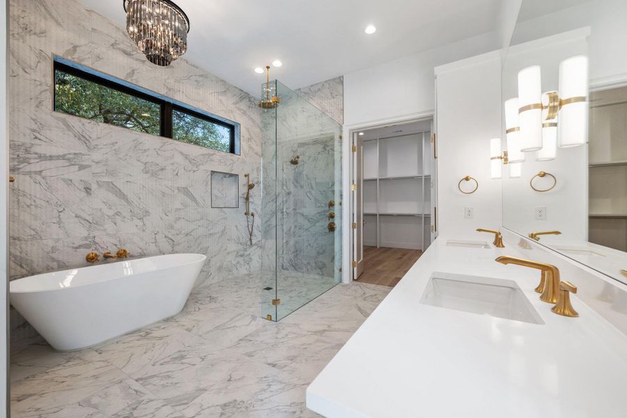 Bathroom with a spacious closet, a marble finish shower, a freestanding tub, suspended lighting, and double vanity