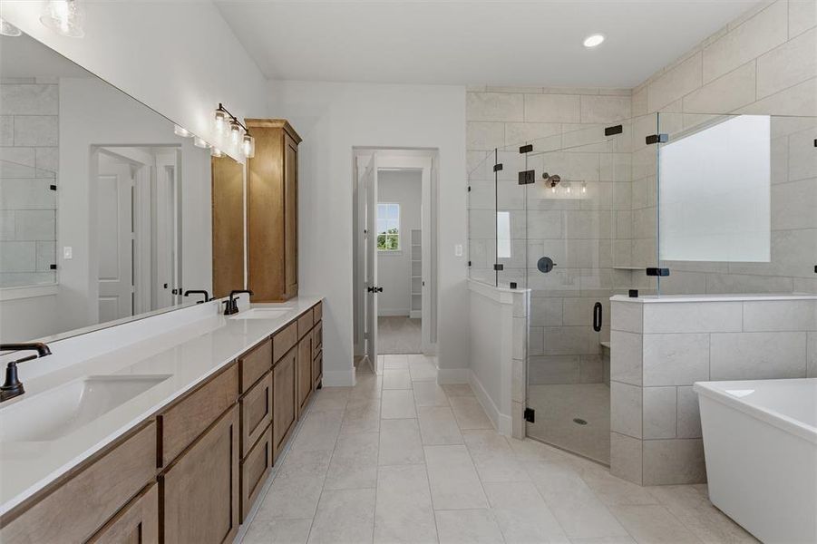 Bathroom featuring a long vanity with dual sinks, an expansive mirror, and a walk-in shower with clear glass enclosure