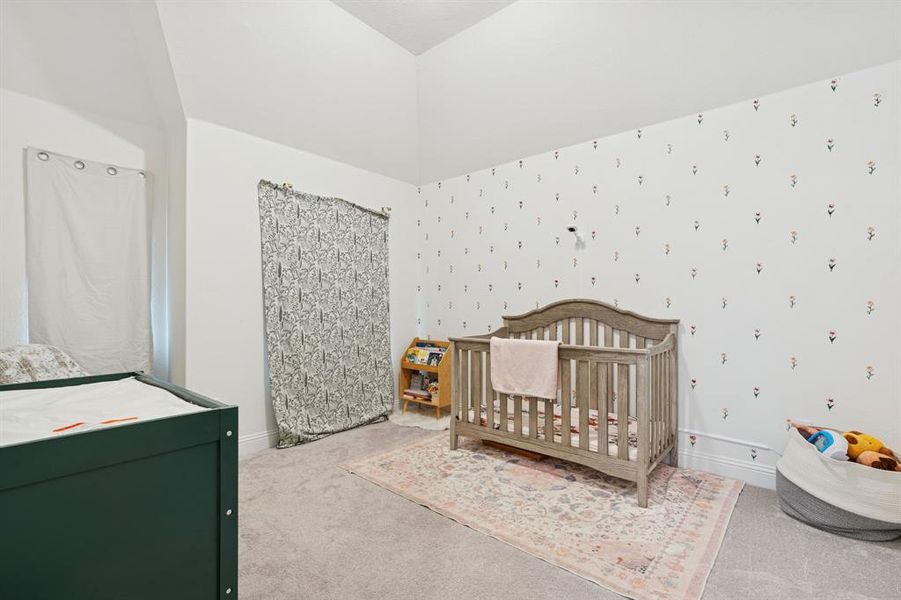 Bedroom with carpet floors, a crib, and wallpapered walls Bedroom with carpet floors, a crib, and wallpapered walls