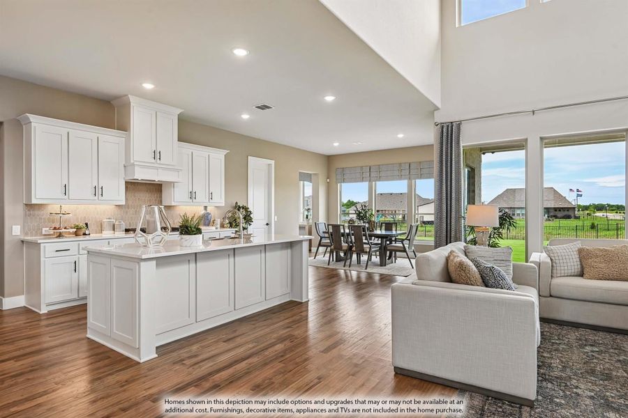 Open-concept kitchen and living area with white cabinets, large island, hardwood floors, and high ceilings Open-concept kitchen and living area with white cabinets, large island, hardwood floors, and high ceilings