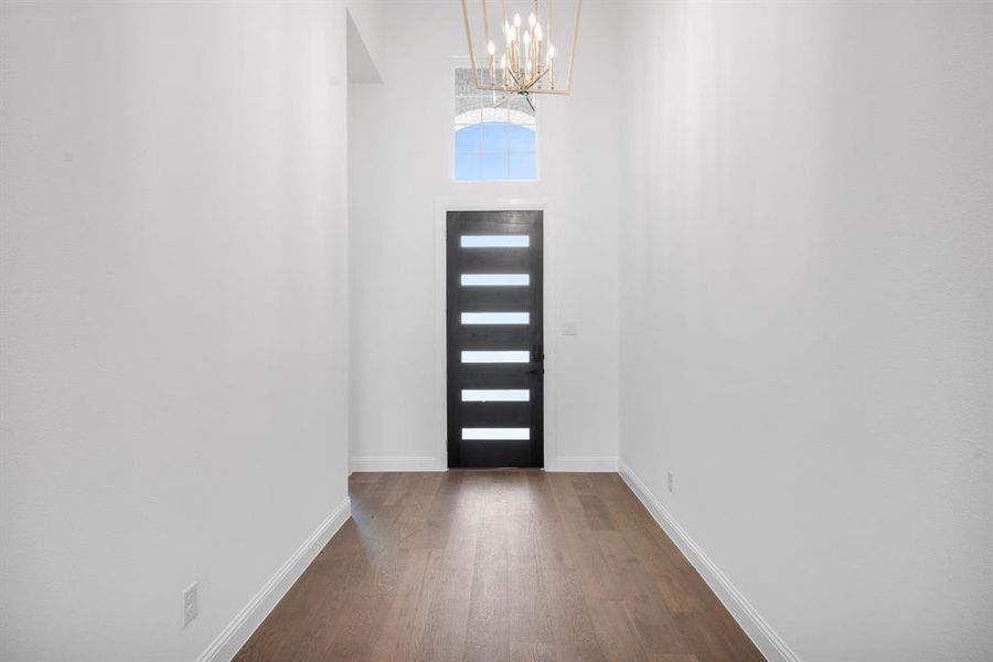 Entrance foyer with dark hardwood / wood-style floors and an inviting chandelier