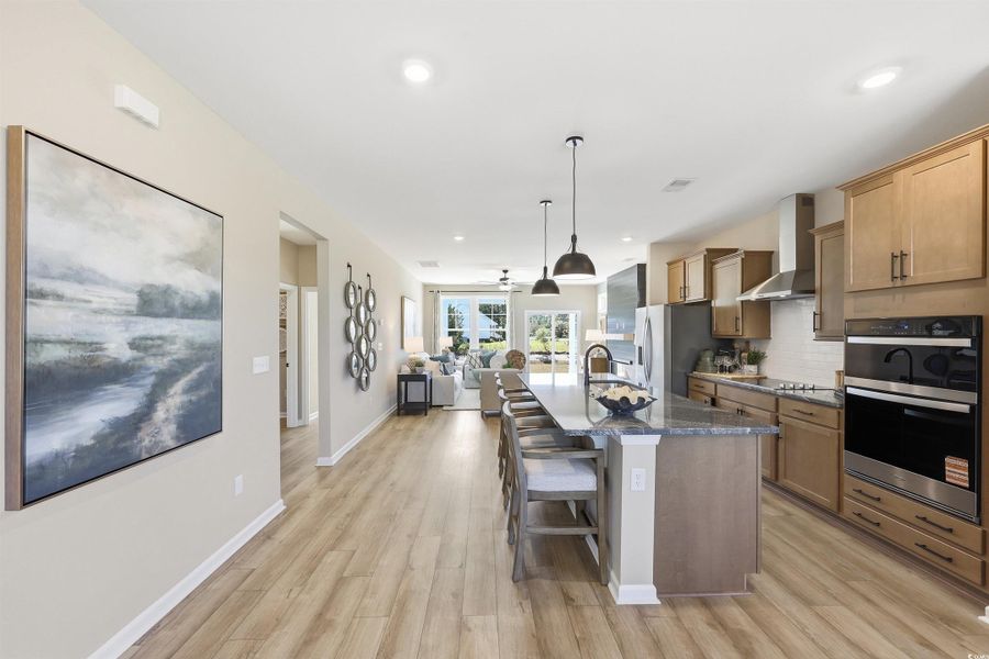 Kitchen featuring a breakfast bar, open floor plan, decorative backsplash, appliances with stainless steel finishes, and hanging light fixtures