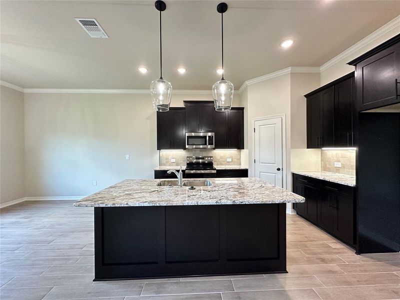 Kitchen with light stone counters, decorative backsplash, wood finish floors, ornamental molding, and recessed lighting