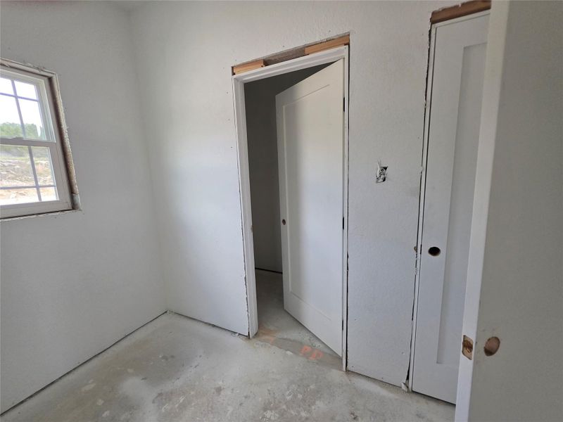 Interior room featuring a double-hung window, two panel doors, and a concrete floor