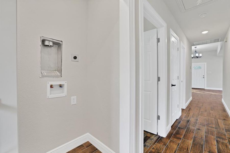 Laundry room featuring an inviting chandelier, hookup for an electric dryer, dark hardwood / wood-style floors, and hookup for a washing machine