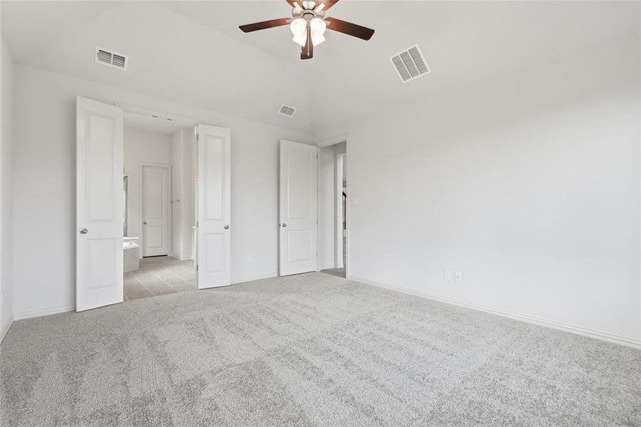 Unfurnished bedroom featuring carpet flooring, lofted ceiling, and a ceiling fan Unfurnished bedroom featuring carpet flooring, lofted ceiling, and a ceiling fan