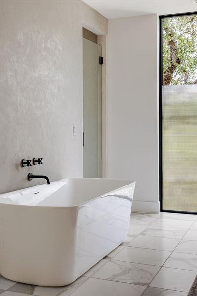 Full bathroom with marble finish floors and a freestanding tub Full bathroom with marble finish floors and a freestanding tub