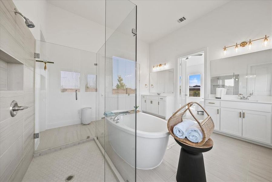 Bathroom featuring visible vents, two vanities, a shower stall, a freestanding tub, and tile patterned floors