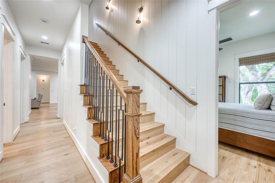 Hardwood staircase featuring dark iron balusters and a rich wood handrail