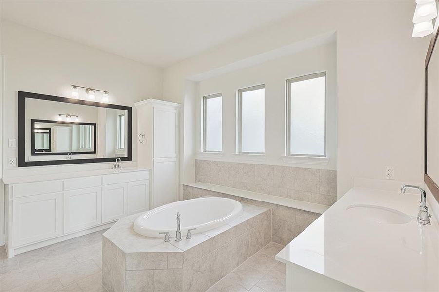 Bathroom with vanity, a healthy amount of sunlight, tile patterned flooring, and tiled bath