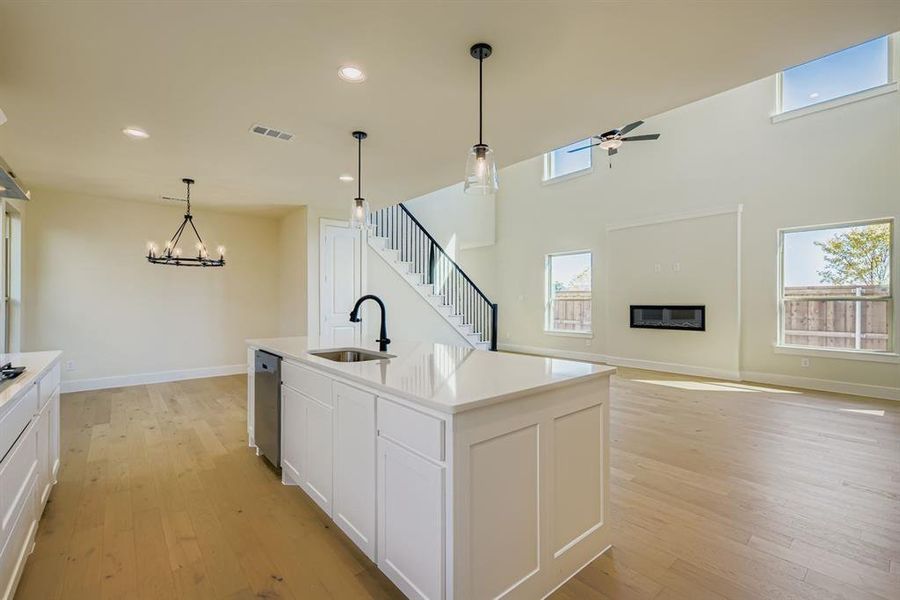 Kitchen featuring hanging light fixtures, open floor plan, light wood finished floors, recessed lighting, and white cabinets