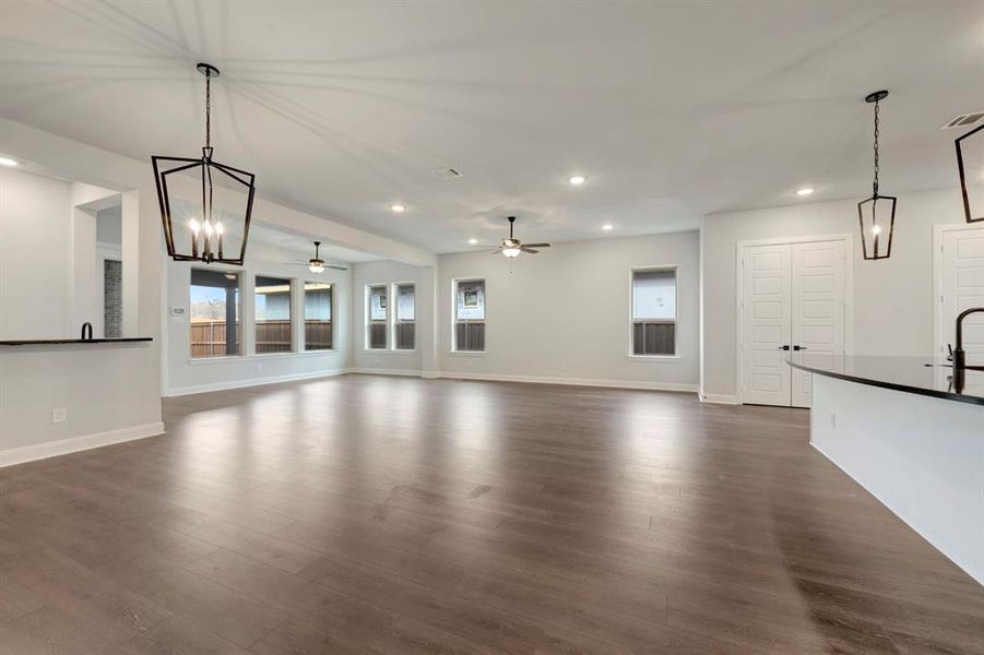 Unfurnished living room with dark wood-style flooring and hanging lights