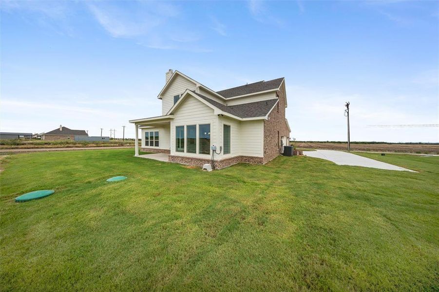 View of property exterior with brick siding, a chimney, a lawn, a shingled roof, and a patio View of property exterior with brick siding, a chimney, a lawn, a shingled roof, and a patio