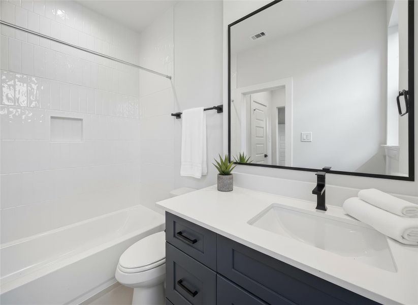 Ensuite bathroom featuring a quartz-topped vanity, matte black fixtures, and a tub-shower combo. *Virtually staged*