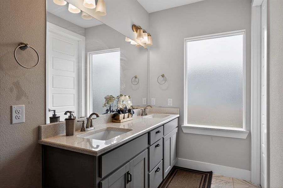 Bathroom featuring a double vanity with a light-colored countertop, dual sinks, and under-sink cabinetry
