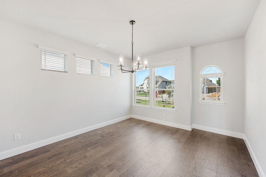 Empty dining room with dark hardwood floors, chandelier, and multiple windows with neighborhood views Empty dining room with dark hardwood floors, chandelier, and multiple windows with neighborhood views