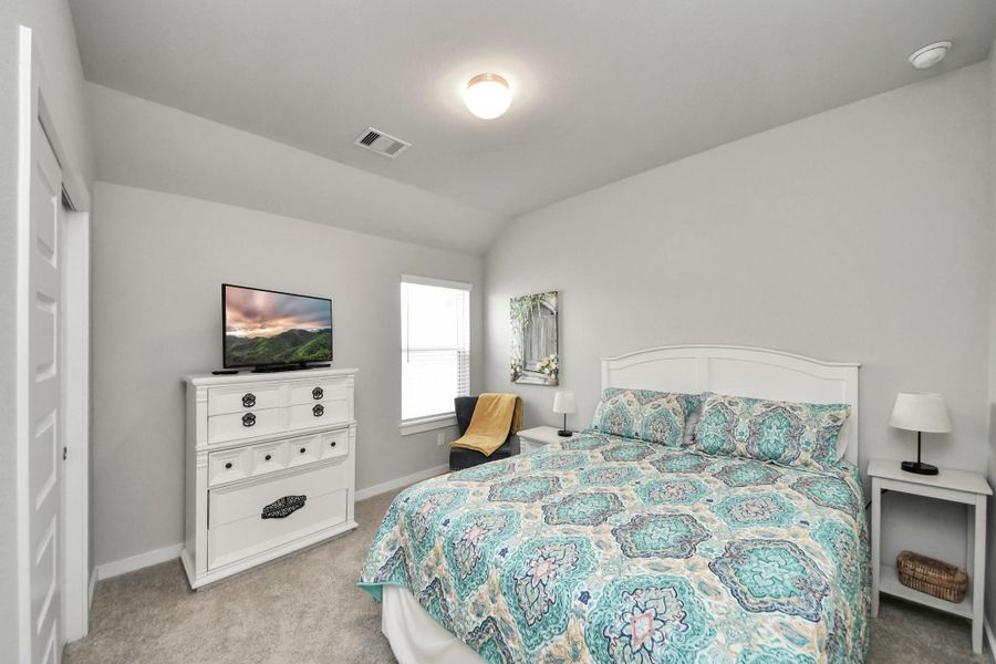 Soft neutral tones and plush carpeting define this quiet secondary bedroom, finished with a roomy closet.