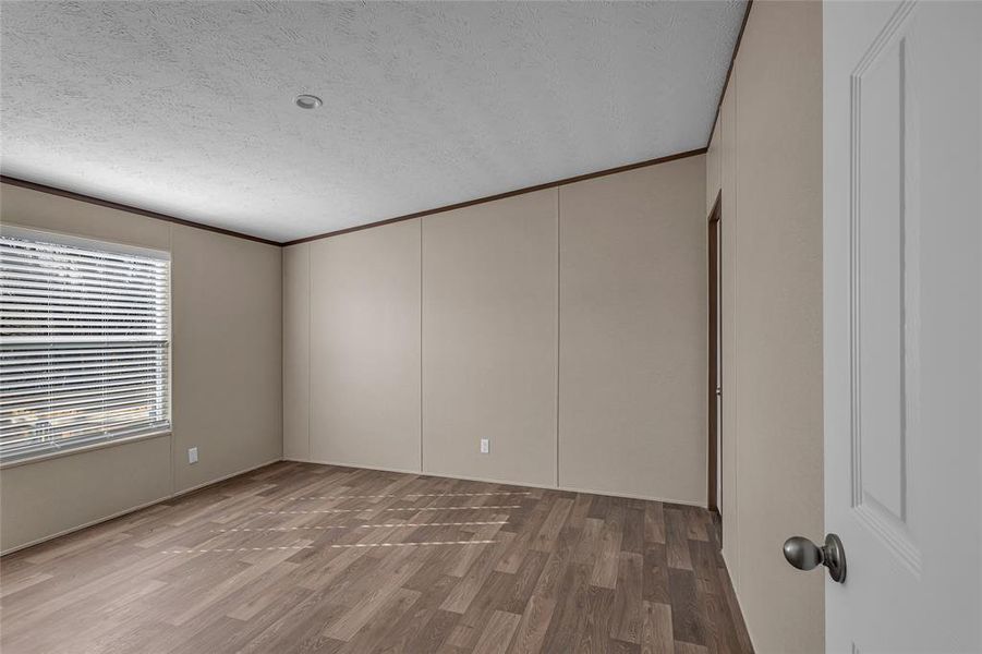 Spare room featuring a textured ceiling, hardwood / wood-style flooring, and crown molding