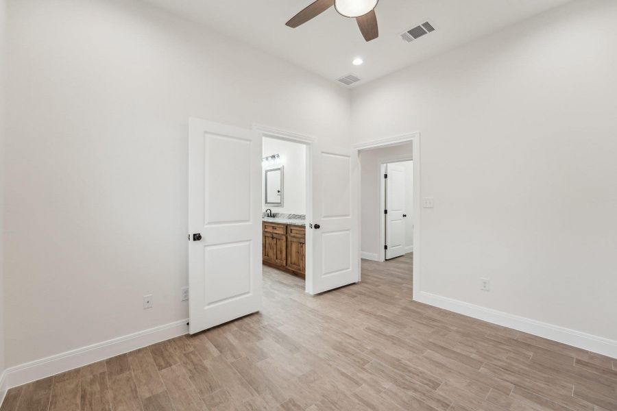 Unfurnished bedroom with baseboards, visible vents, and wood plank tile floor Unfurnished bedroom with baseboards, visible vents, and wood plank tile floor