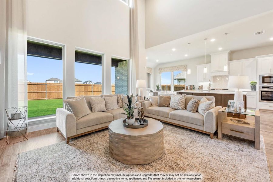 Open-concept living room with two-story ceiling, large windows, and view into white kitchen Open-concept living room with two-story ceiling, large windows, and view into white kitchen