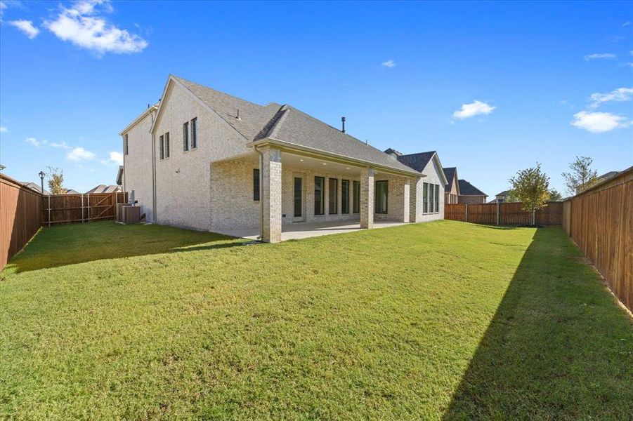 Back of house with a patio area, a fenced backyard, brick siding, and roof with shingles