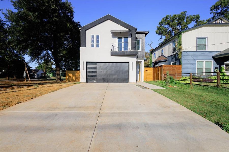 Modern home featuring a balcony, stucco siding, concrete driveway, and a garage Modern home featuring a balcony, stucco siding, concrete driveway, and a garage