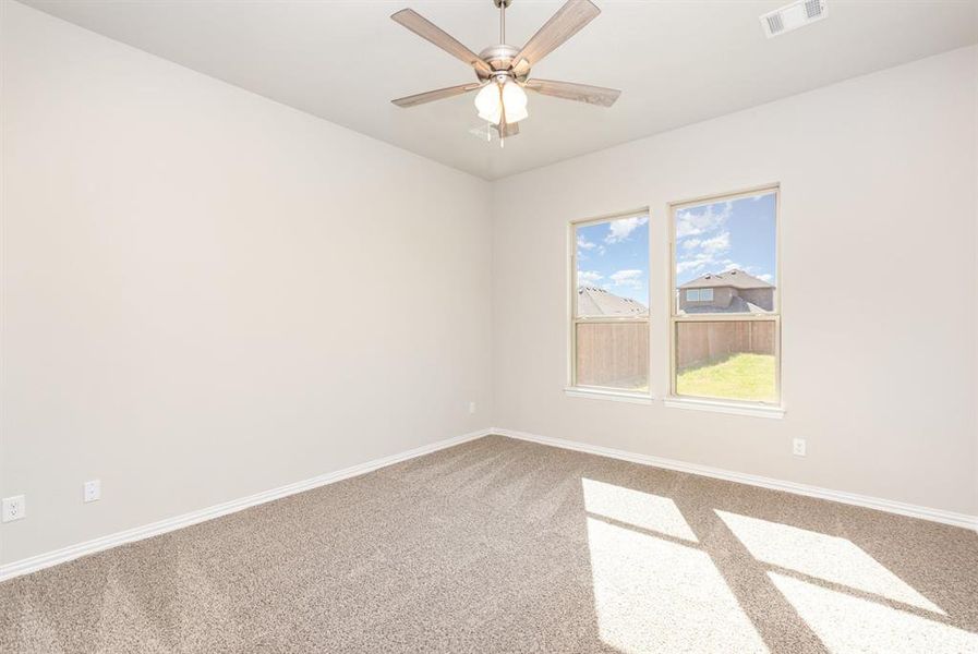 Carpeted spare room featuring baseboards, visible vents, and ceiling fan