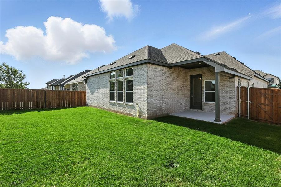 Rear view of property with a fenced backyard, brick siding, a patio area, a gate, and roof with shingles