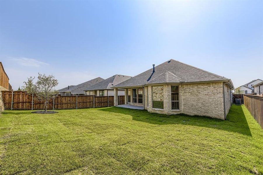 Back of property with brick siding, a patio area, a fenced backyard, and a shingled roof