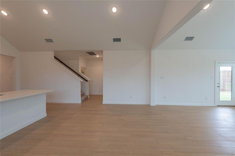 Empty room with light colored carpet, baseboards, and lofted ceiling