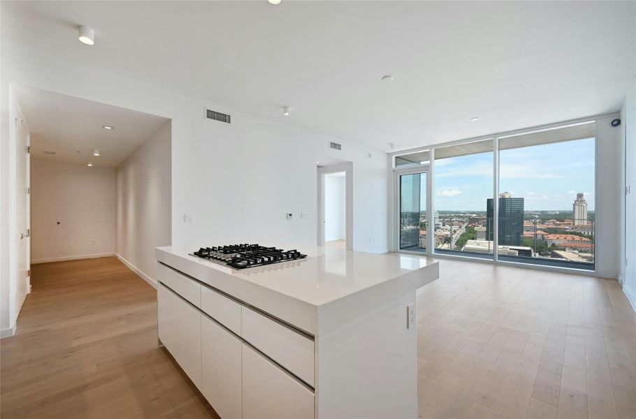 Sophisticated open-concept kitchen featuring sleek Bosch appliances, integrated wood-paneled cabinetry, and a glossy white island ideal for casual dining or entertaining—all seamlessly connected to the main living space with clean, modern lines.