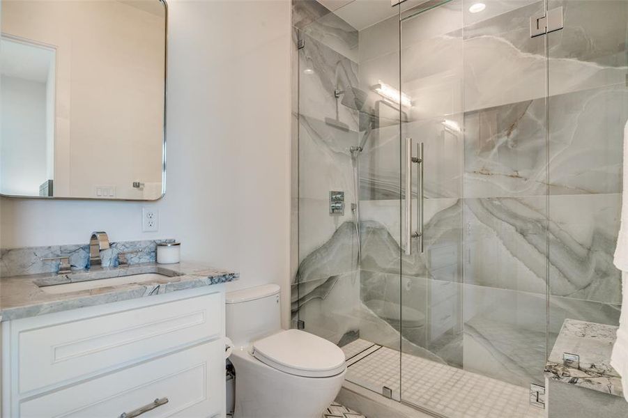 Bathroom featuring a shower with shower door, vanity, and toilet