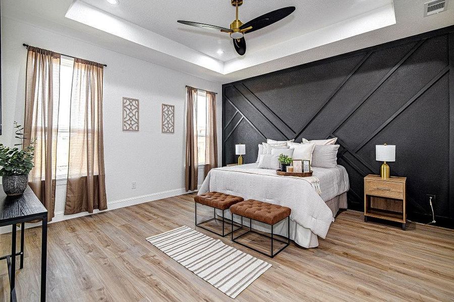 Bedroom featuring visible vents, baseboards, a tray ceiling, recessed lighting, and light wood-style floors