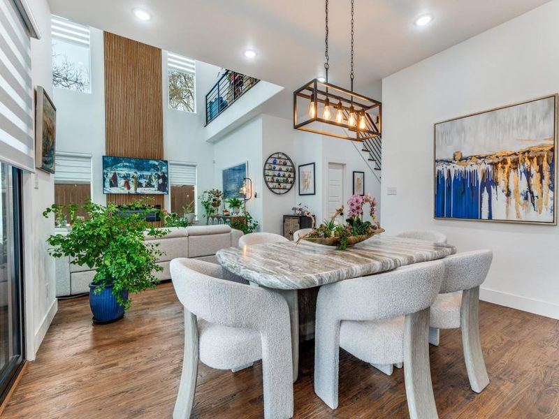 Dining area featuring stairs, a high ceiling, recessed lighting, wood finished floors, and a chandelier