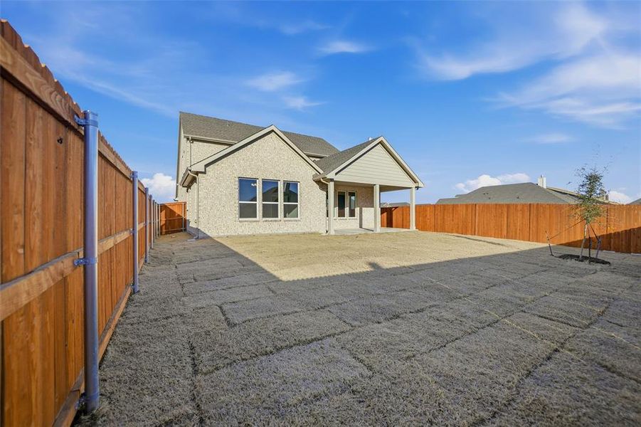 Back of house with a fenced backyard, a patio area, and brick siding Back of house with a fenced backyard, a patio area, and brick siding