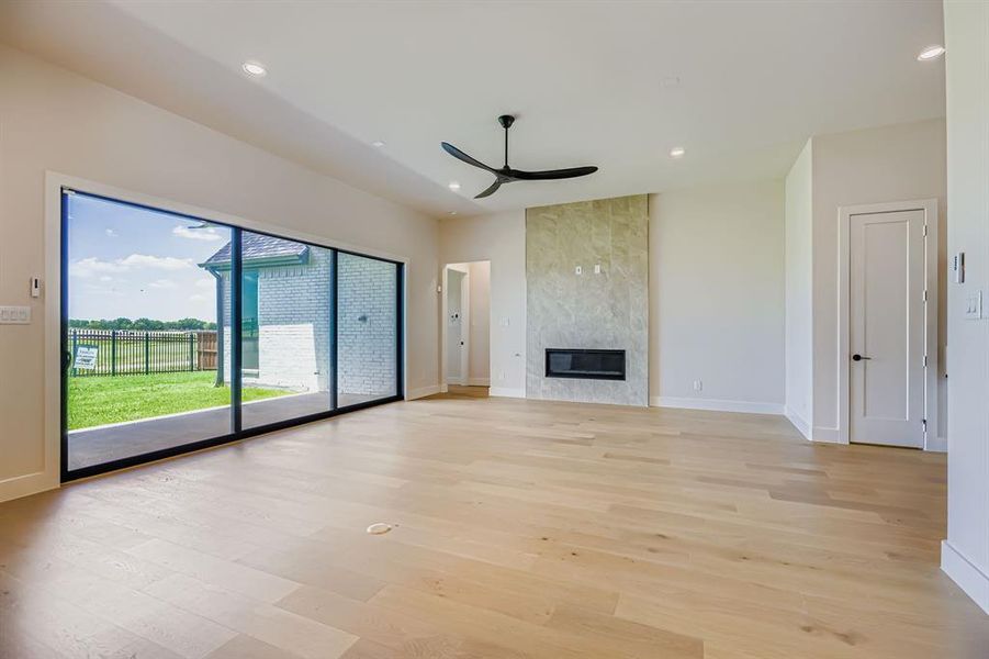 Unfurnished living room featuring ceiling fan, light wood-type flooring, recessed lighting, and a fireplace