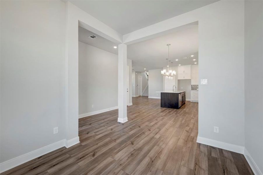 Unfurnished living room featuring light wood-style flooring and suspended lighting