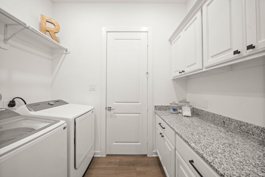 Connected to the owner’s closet, the laundry room offers plenty of space for a full-size washing machine and dryer, along with a folding station with granite countertop and cabinet storage above and below to keep everything organized.