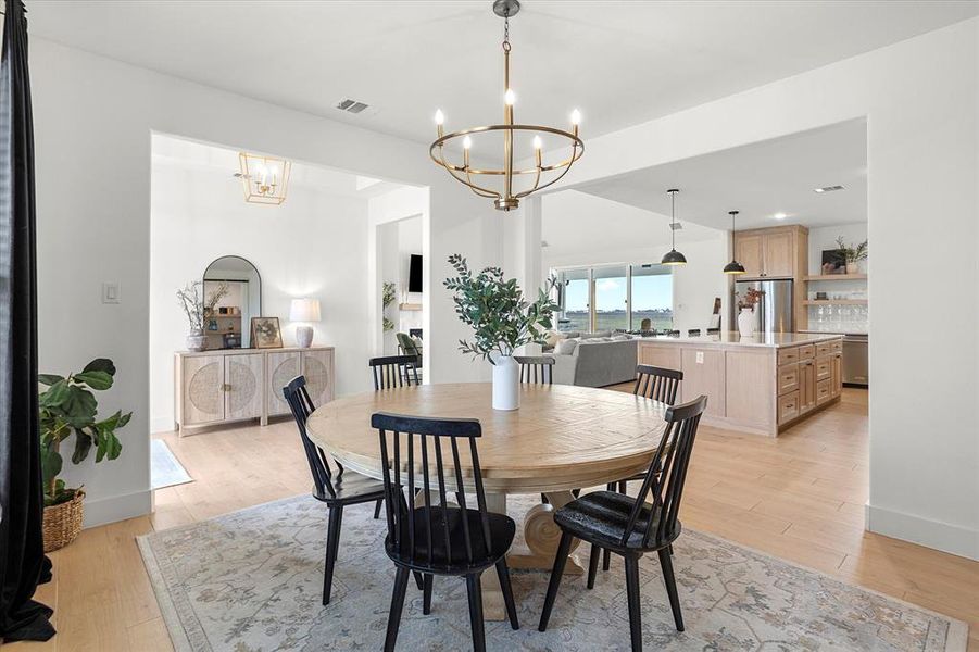 Dining space with light hardwood / wood-style floors and an inviting chandelier