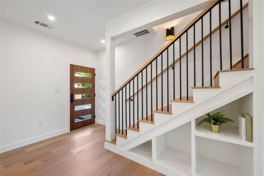 A striking modern wooden door welcomes guests, complemented by rich hardwood flooring. A striking modern wooden door welcomes guests, complemented by rich hardwood flooring.