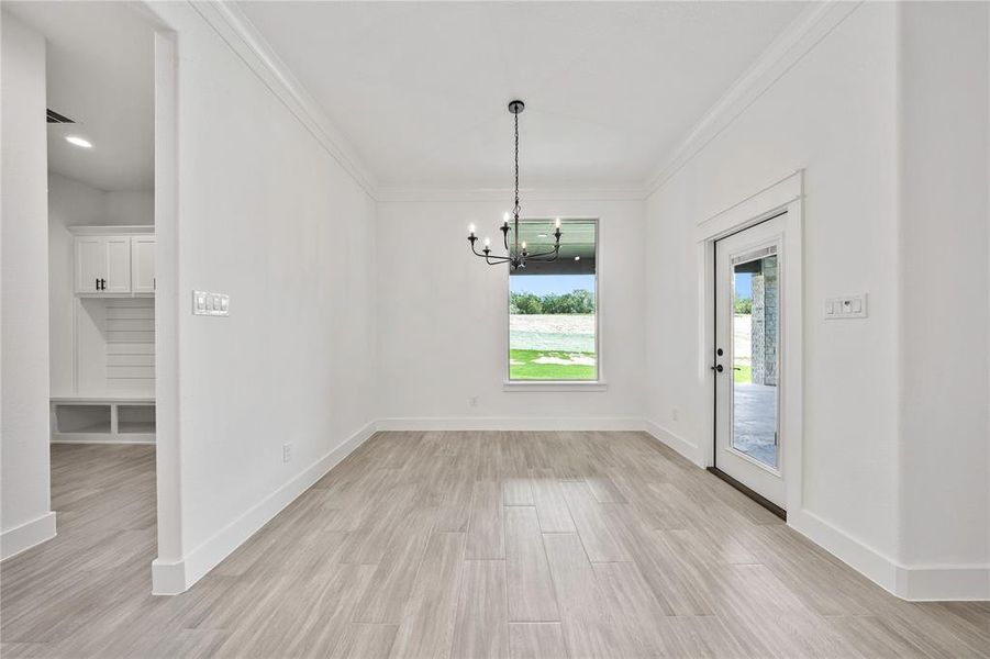 Unfurnished dining area with a chandelier, ornamental molding, and light wood-style flooring Unfurnished dining area with a chandelier, ornamental molding, and light wood-style flooring