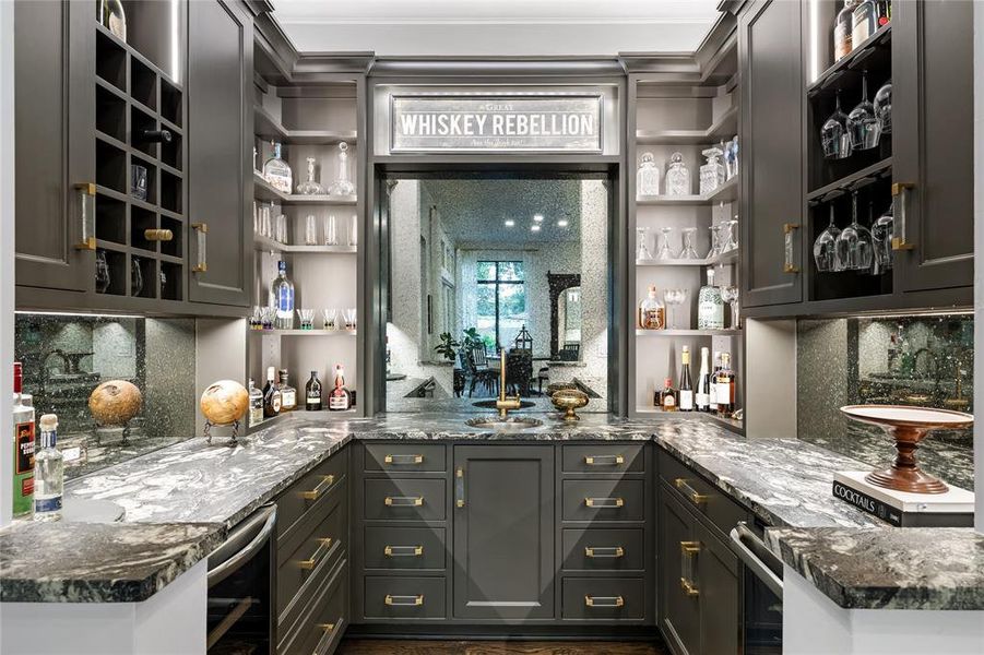 Bar with tasteful backsplash, dark stone countertops, and beverage cooler