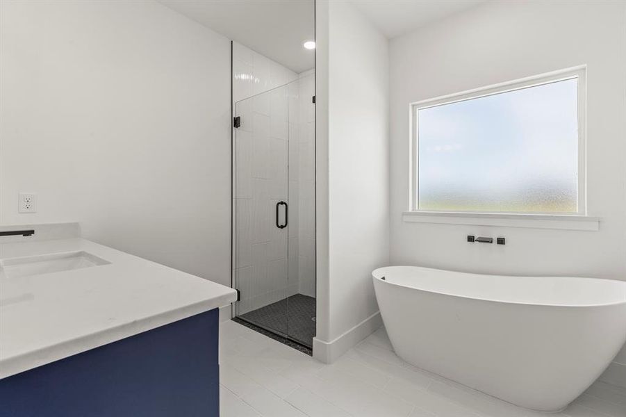 Full bath featuring a stall shower, a freestanding bath, vanity, and tile patterned flooring