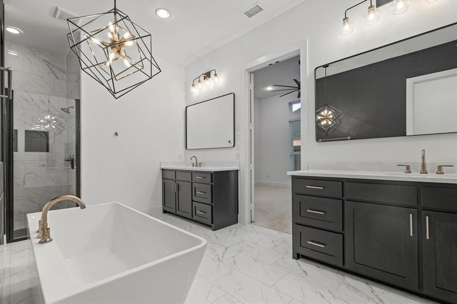 Bathroom with a chandelier, a marble finish shower, a freestanding bath, two vanities, and recessed lighting Bathroom with a chandelier, a marble finish shower, a freestanding bath, two vanities, and recessed lighting