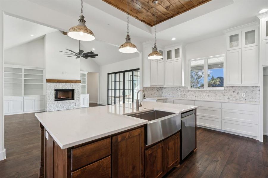 Kitchen featuring stainless steel dishwasher, sink, a center island with sink, white cabinets, and lofted ceiling