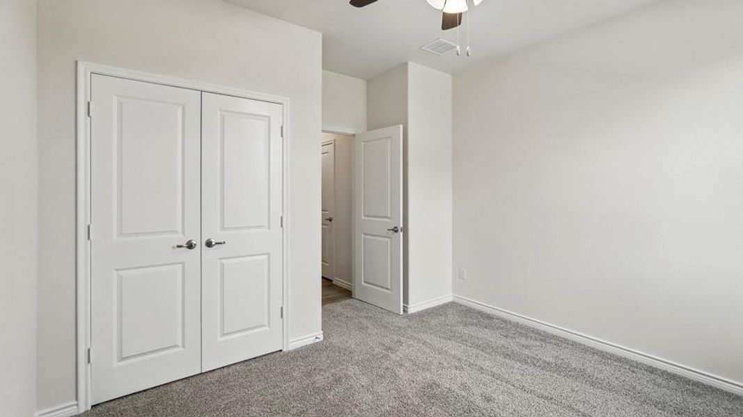 Bedroom featuring grey carpet flooring, white walls, white baseboards, and a white paneled closet with satin nickel hardware