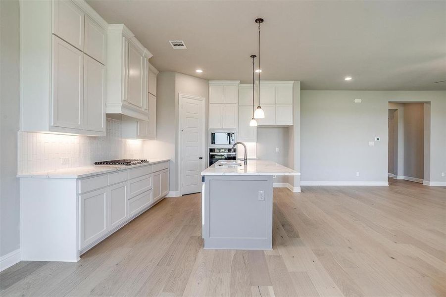 Kitchen featuring a kitchen island with sink, white cabinetry, and light hardwood / wood-style flooring