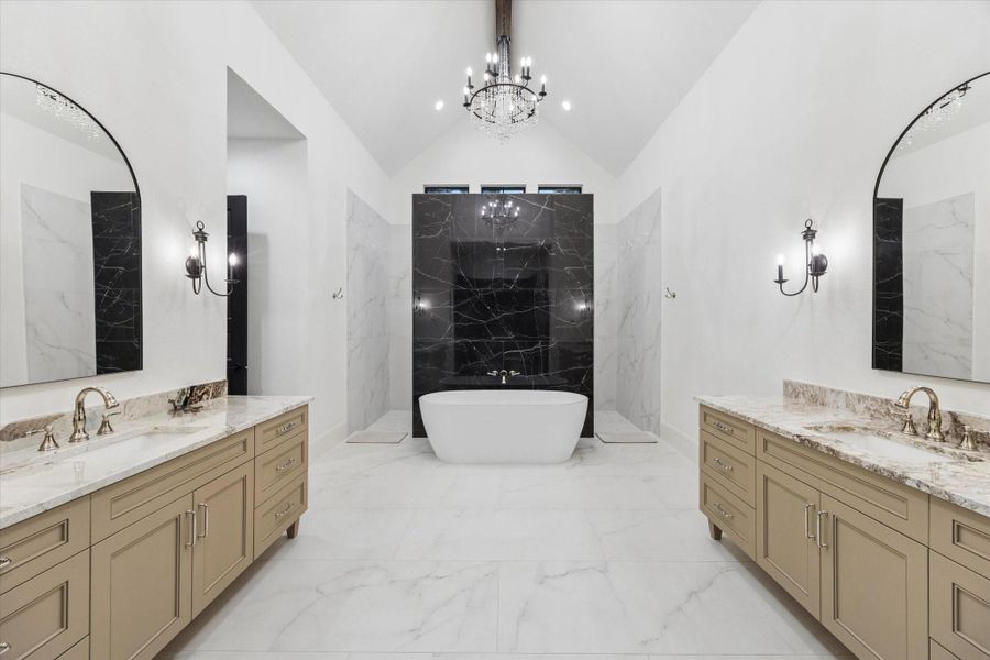 The spa-inspired primary bath delivers a true luxury experience. Dramatic stone surfaces, soaring ceilings, dual vanities, and exquisite craftsmanship surround a freestanding soaking tub, creating a tranquil setting designed for everyday relaxation.